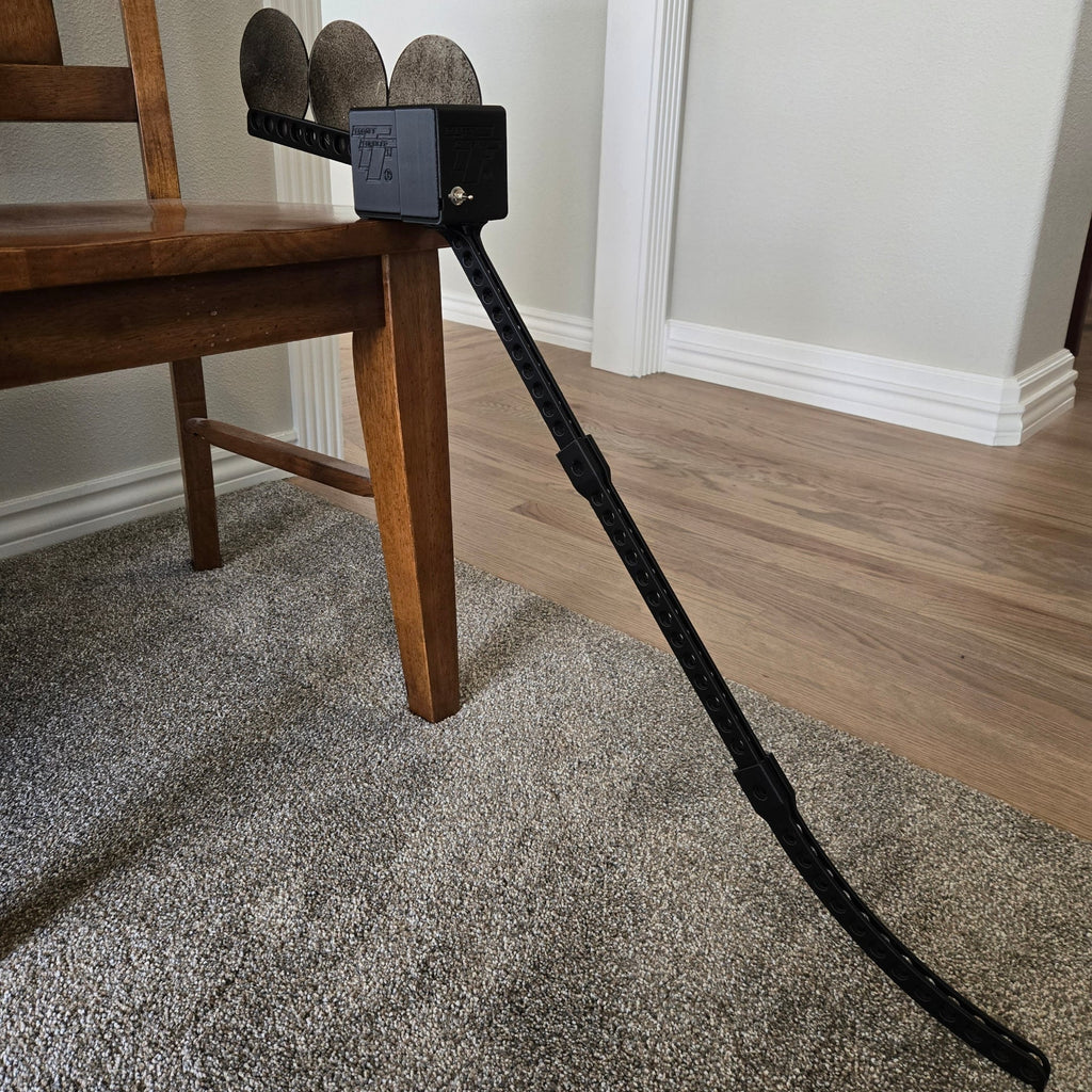 Black cable with shoes attached, on a carpeted floor next to a wooden chair.