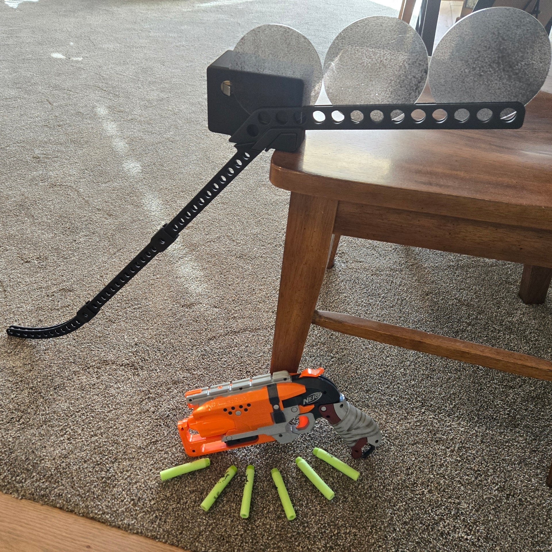 Toy gun with darts on a carpeted floor next to a wooden chair